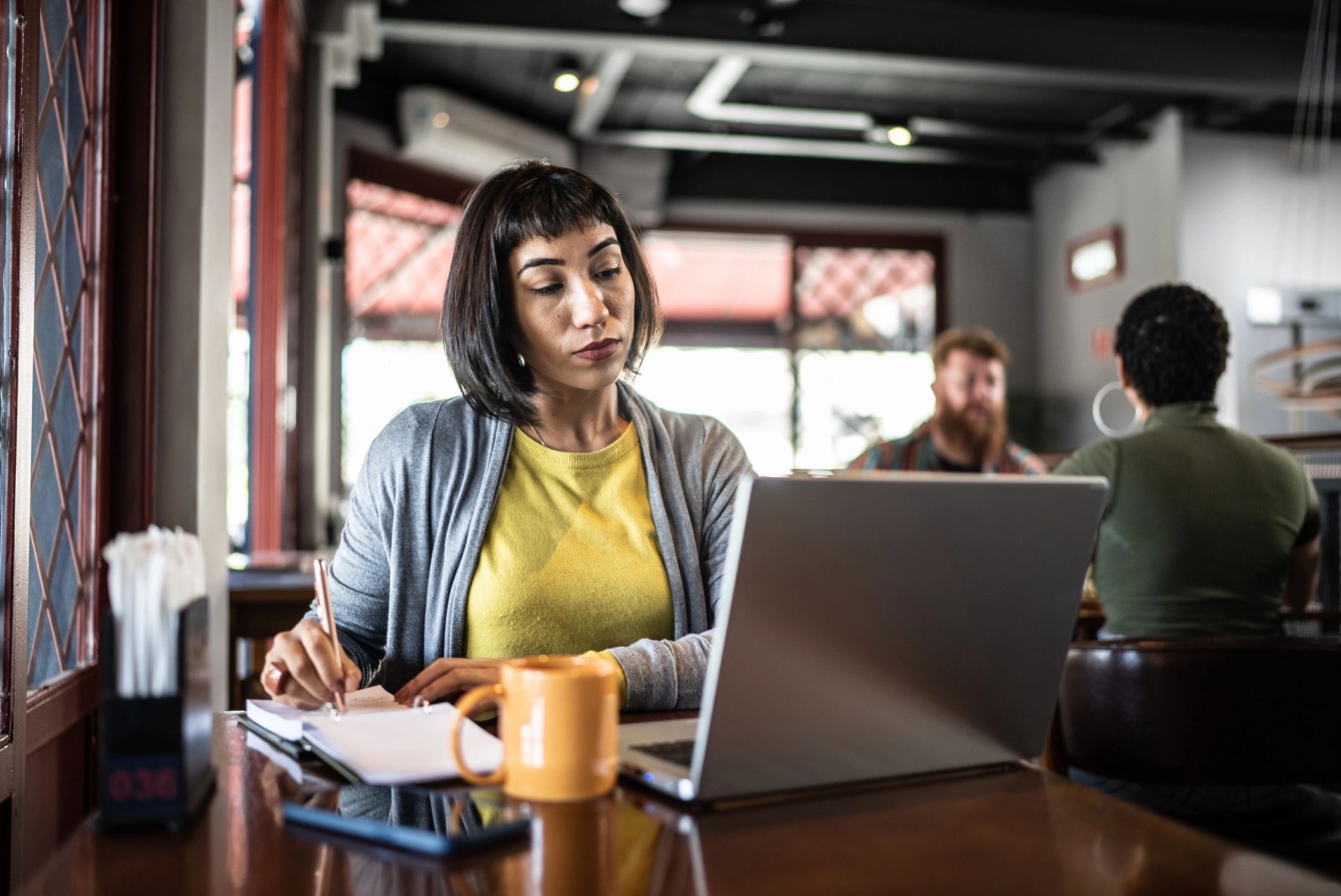 Woman journaling beside a laptop while planning her next step