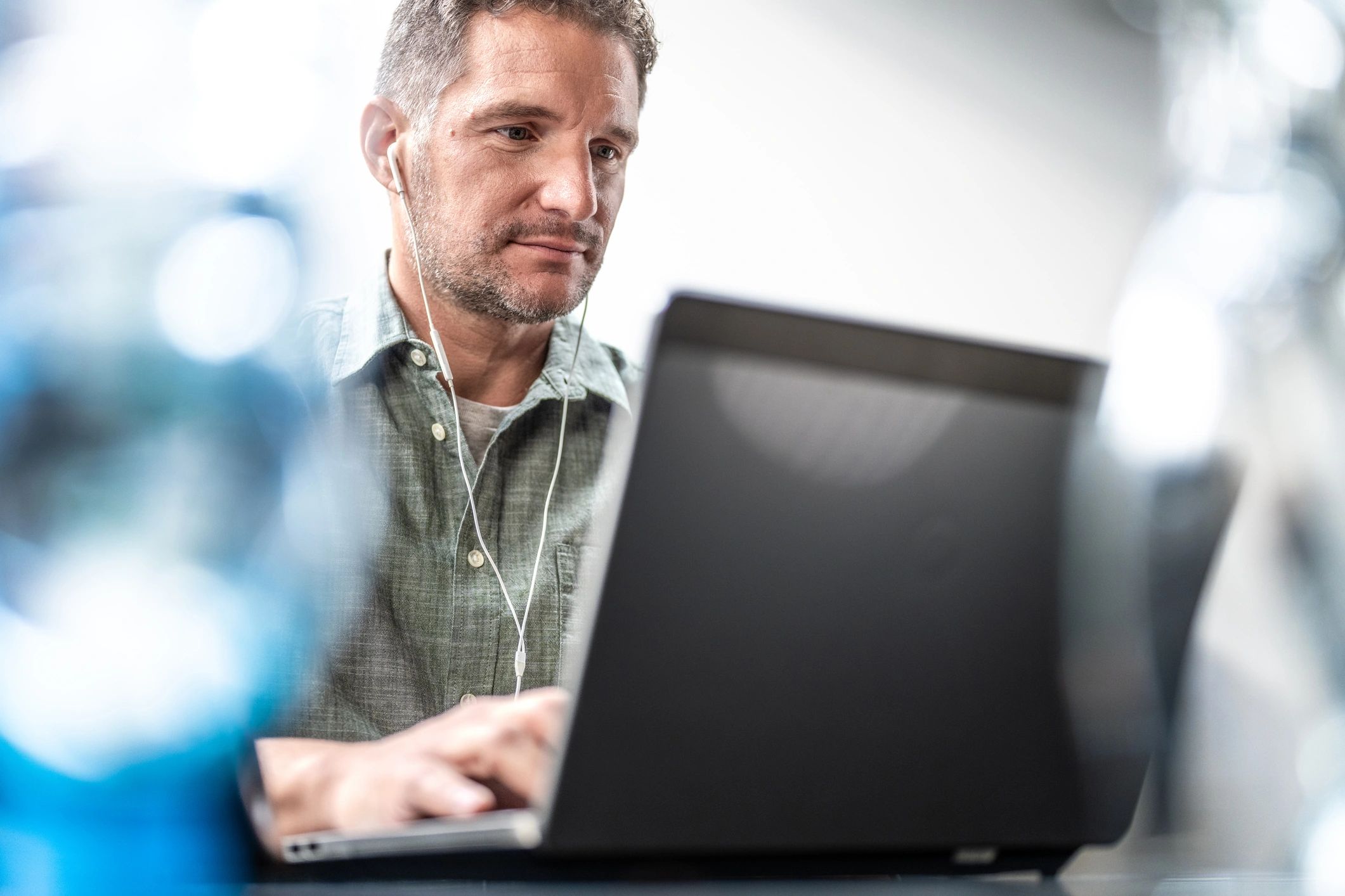 Man working on a laptop in an office with earphones