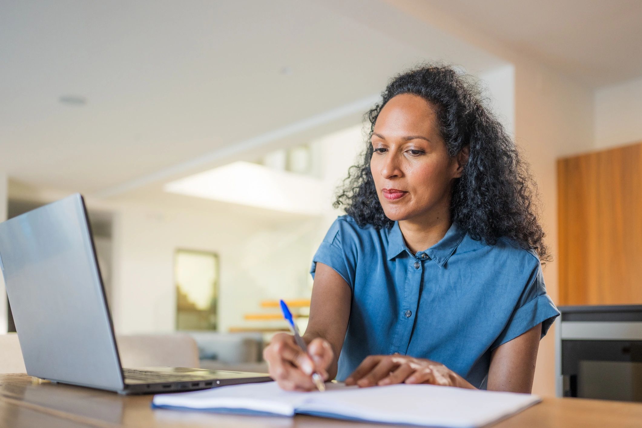 Woman journaling and taking notes while learning online