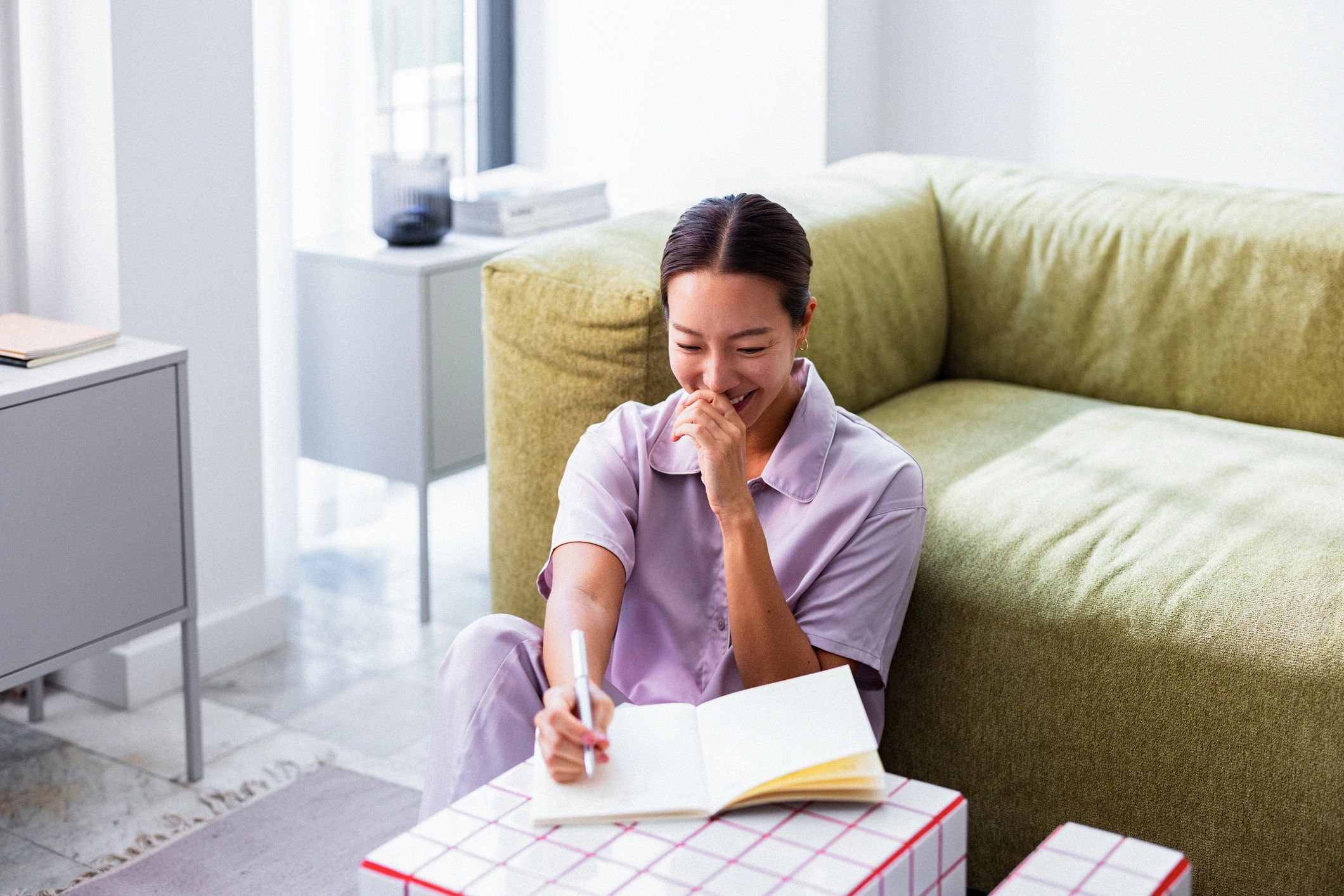 Woman journaling at home beside a sofa