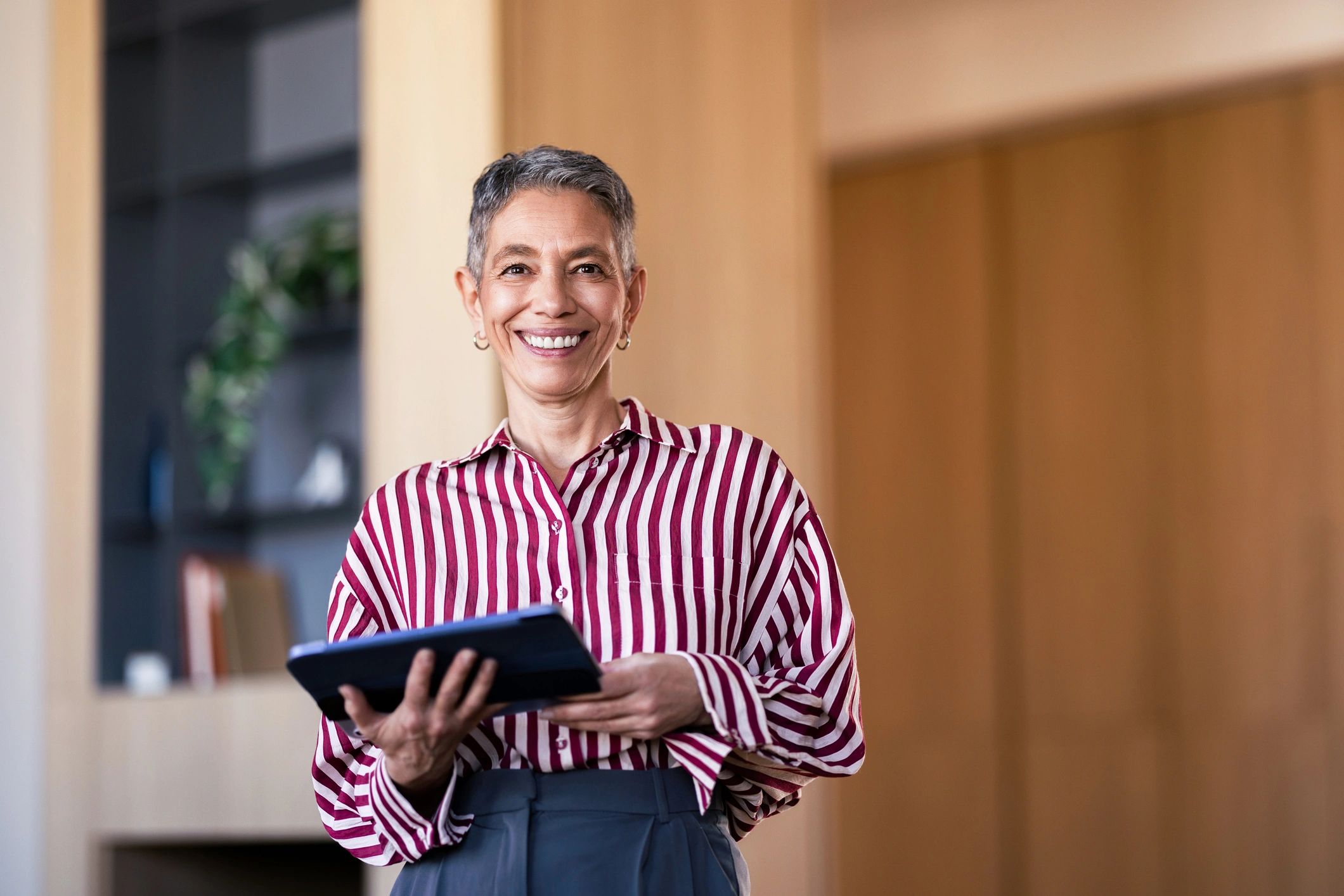 Confident professional woman holding a tablet in a modern office