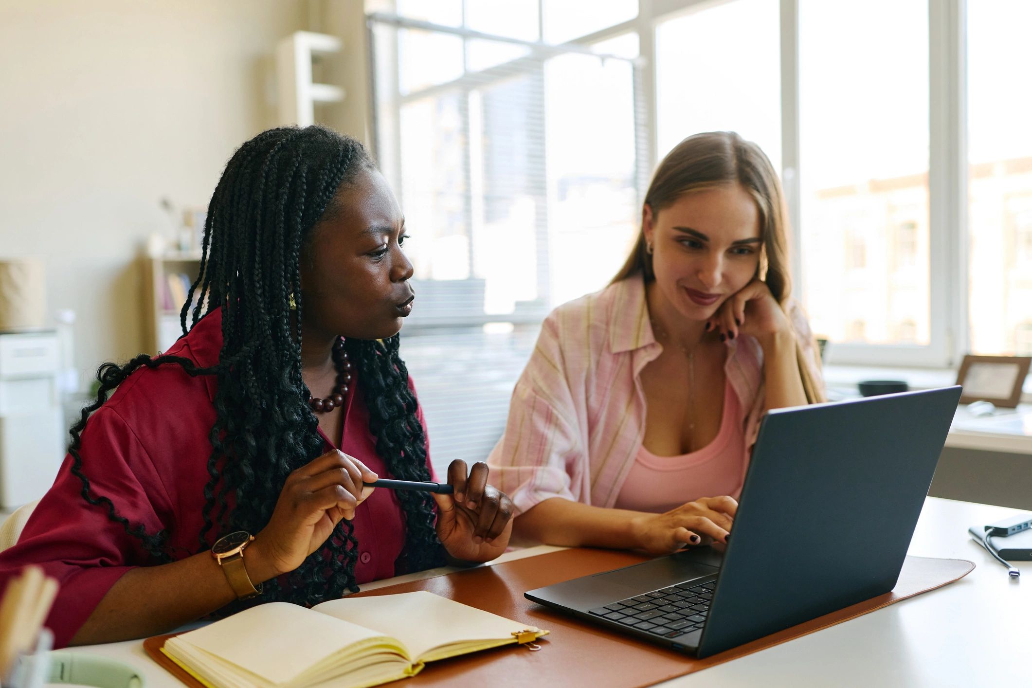 Two women collaborating at a desk with a laptop